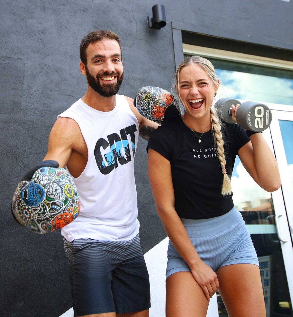 Charleston coaches pose with a weight and boxing gloves outside of the studio